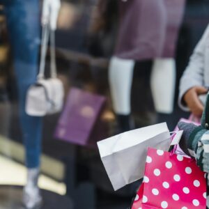 Crop anonymous women friends in stylish clothes standing with shopping bags near counter of boutique in daytime