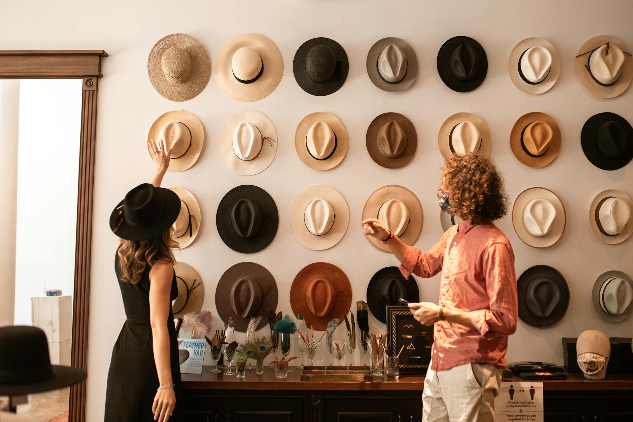 Elegant hat display in a fashion boutique with two stylish adults browsing.