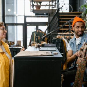 Two young adults interacting at a fashionable boutique, emphasizing style and shopping.